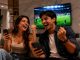 Pareja celebra viendo fútbol en casa con móviles