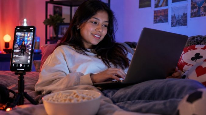 Mujer usando un portátil junto a un smartphone con una red social abierta